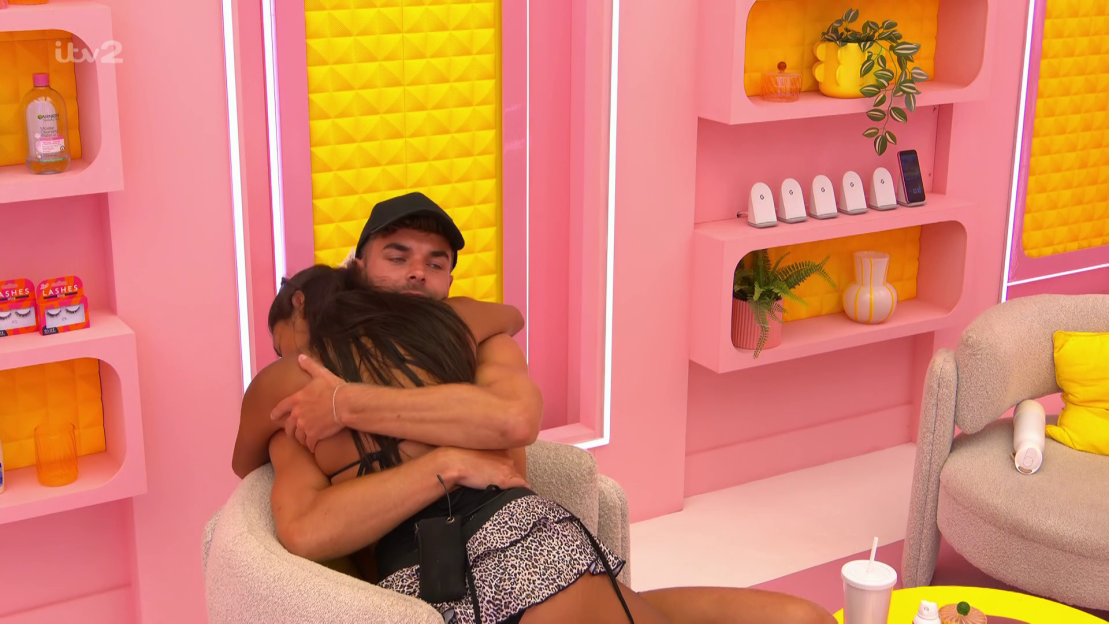 Couple embracing on a pink couch.