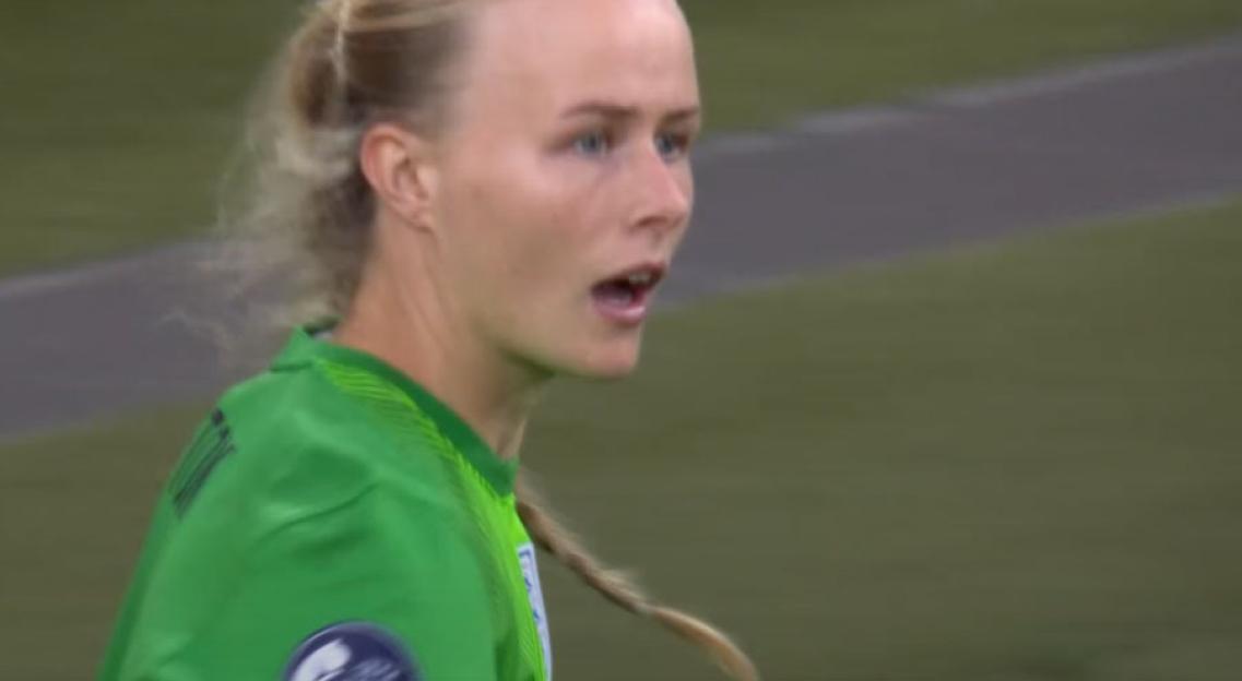 Close-up of a female soccer goalie in a green uniform.