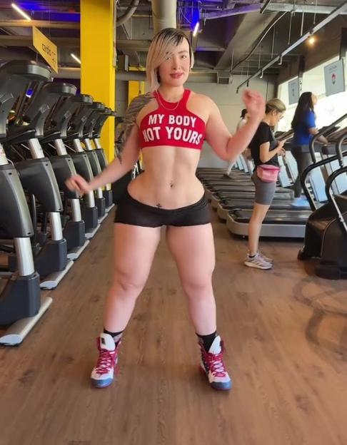 Woman in a gym wearing a red top that says