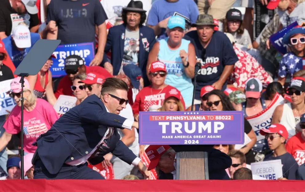 Man in suit interacting with Trump 2024 rally crowd.