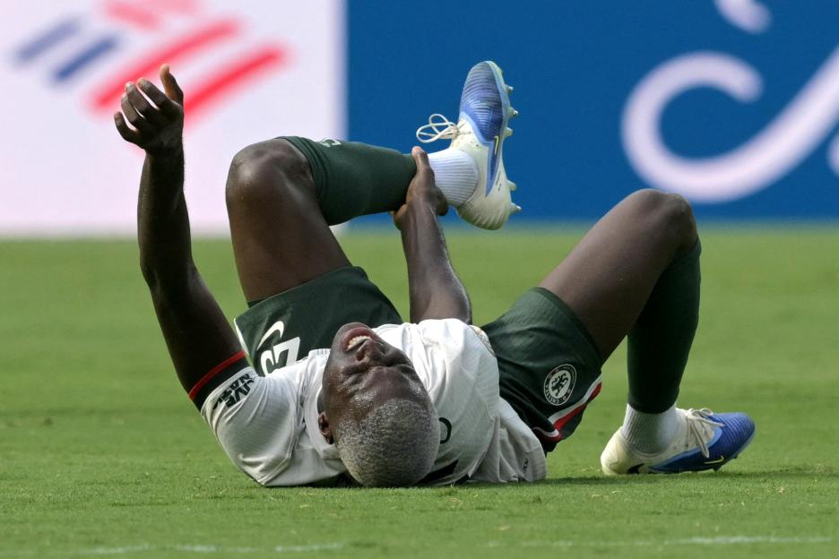 Soccer player on the ground clutching his leg in pain.