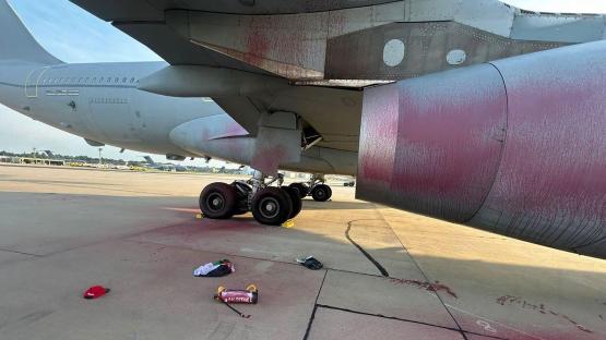 Vandalized military aircraft with paint splattered on its wing and fuselage.