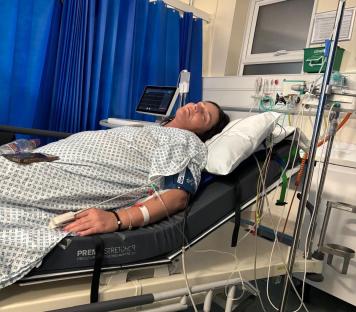 Woman lying in a hospital bed hooked up to medical equipment.