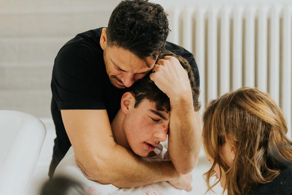 A man comforts a wounded young man.