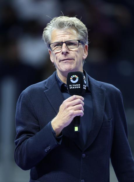 Andrew Castle, former tennis player and broadcaster, holding a microphone.
