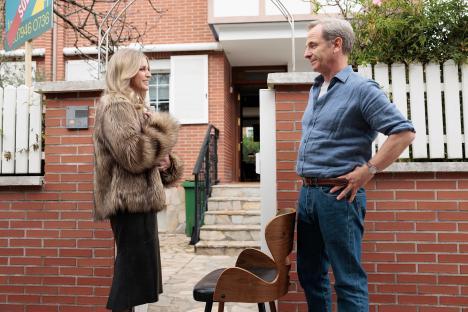 A man and woman stand outside a house, talking.