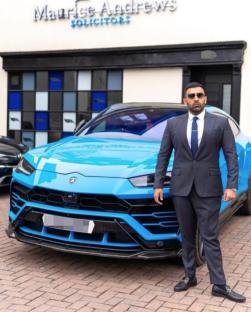 Man in suit standing in front of blue Lamborghini Urus.