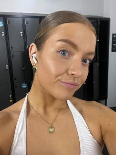 Woman wearing wireless earbuds and a gold necklace.