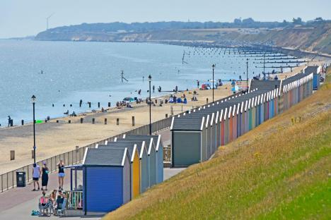 Beach with colorful beach huts and people enjoying the sun.
