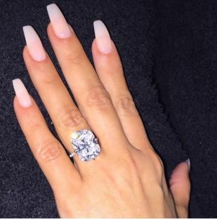 Hand with large diamond ring and long nails.