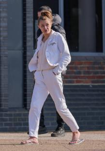 Woman in white pants and jacket outside a courthouse.