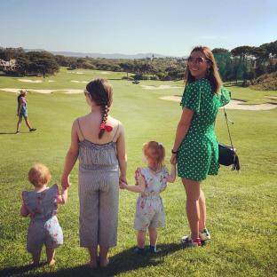 Woman and three girls on a golf course.