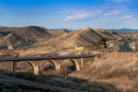 Stone bridge over a dry riverbed in a desert landscape.