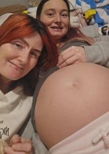Photo of two women, one pregnant, cuddling.