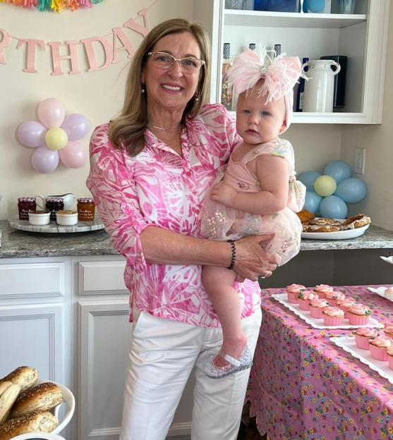 a woman holds a baby in front of a birthday banner