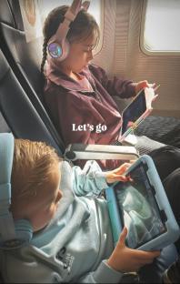 Two children on an airplane using tablets.