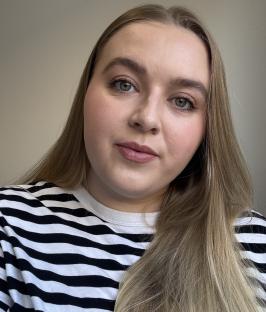 Woman with long blonde hair wearing a black and white striped shirt.