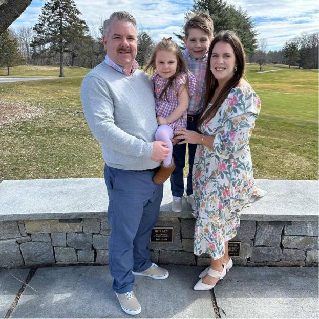 Family photo of four people in front of a stone wall.