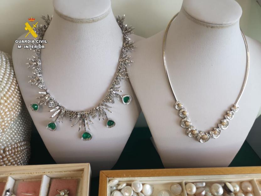 Recovered stolen jewelry, including two necklaces on white busts and a box of pearls.