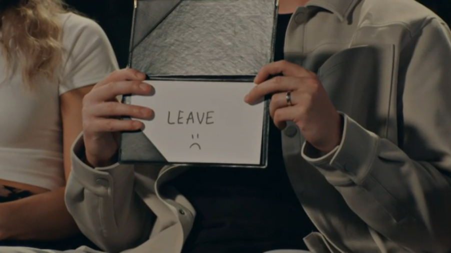 A person holding a card with the word "LEAVE" and a sad face drawn on it.