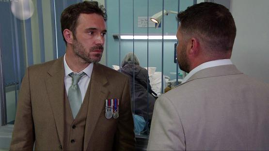Aaron Dingle in a suit, talking to another man.