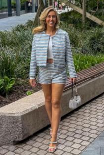 Woman in a blue striped suit and heels walking outside.