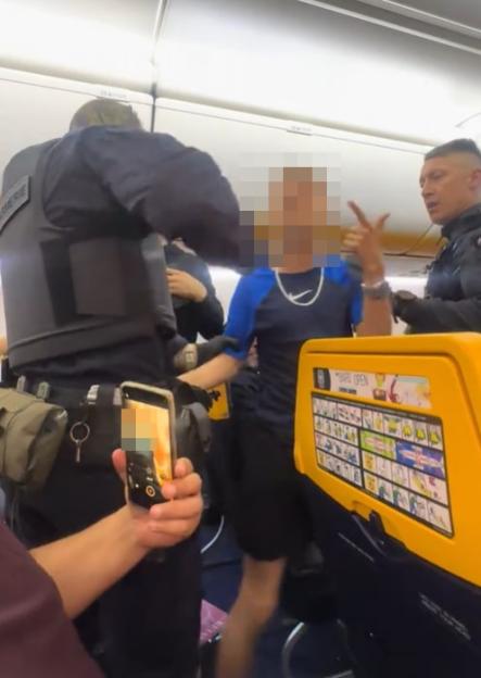 Armed police removing a passenger from a Ryanair flight.