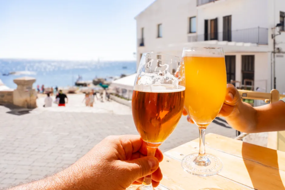 Two people toasting with beers outdoors.