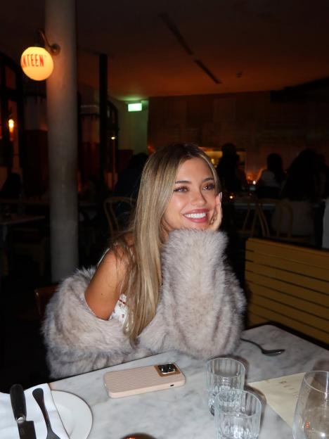 Talitha Balinska smiling while seated at a restaurant table.