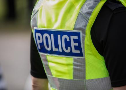 Police officer's back, showing a high-visibility vest with 