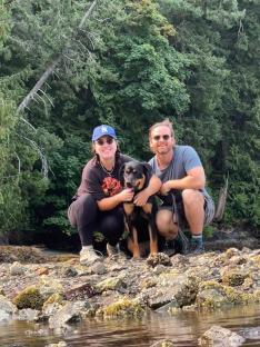 Couple and dog posing by the water.