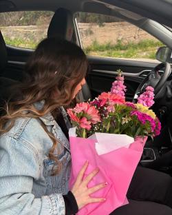 Woman holding a bouquet of pink flowers in a car.