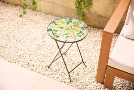 Small lemon-patterned glass-top side table on patio.
