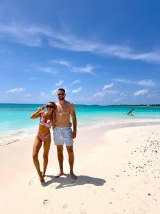 Couple in swimsuits on a tropical beach.