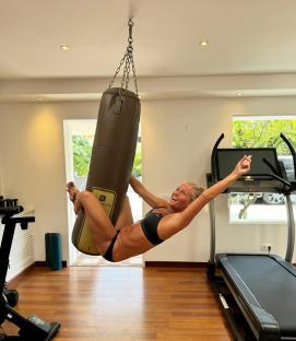 Woman hanging from a punching bag in a gym.