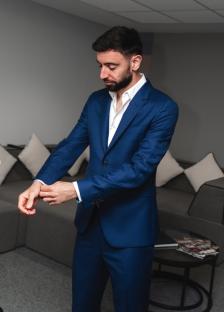 Man adjusting his blue suit jacket.