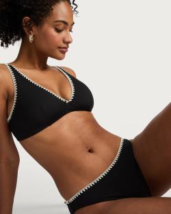 Woman modeling a black bikini with cream trim.
