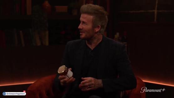 David Beckham holding a jar during an interview.