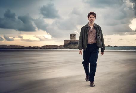 Damien Molony as Jim Bergerac walking on a beach.