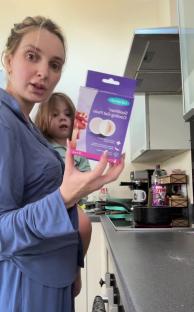 Woman holding cooling gel pads and toddler in kitchen.