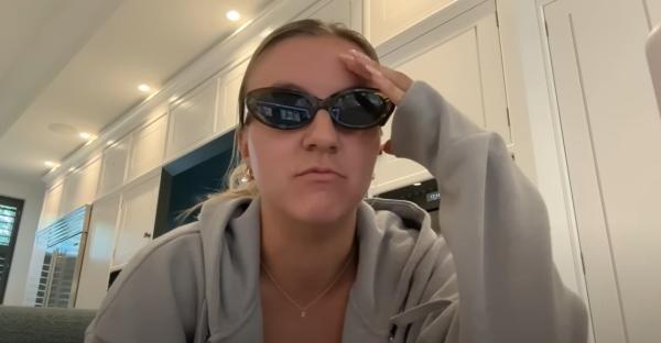 Woman wearing sunglasses and a gray hoodie.