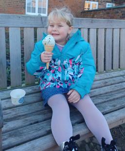 Girl eating ice cream on a bench.
