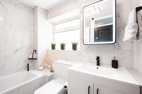 Newly fitted modern bathroom with white marble-effect tiles and black fixtures.