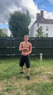 Teenager shirtless in backyard, preparing to dance.