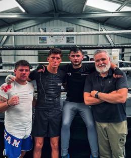 Four men in a boxing gym.