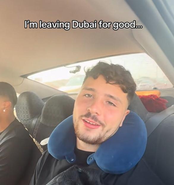 A man with a neck pillow in a car says "I'm leaving Dubai for good..."