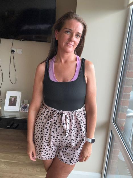 Woman wearing a black tank top and pink shorts.