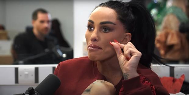 Katie Price in an interview, touching her face.