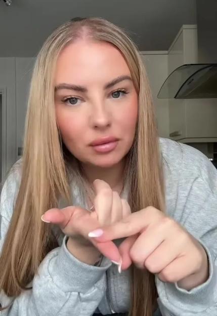 A woman with long blonde hair making a gesture with her hands, as if counting.