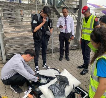 Airport security officers inspecting a suitcase containing drugs.